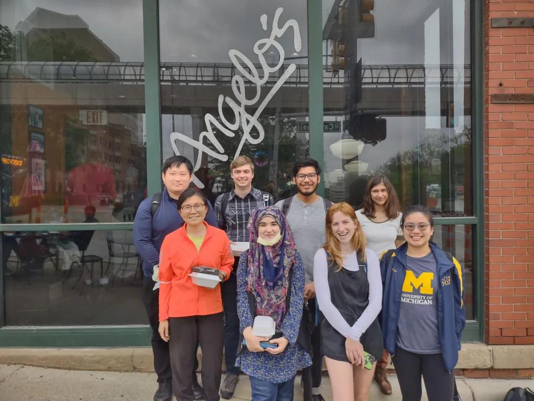 Mahnoor with a group of people standing in front of Angelo's restaurant