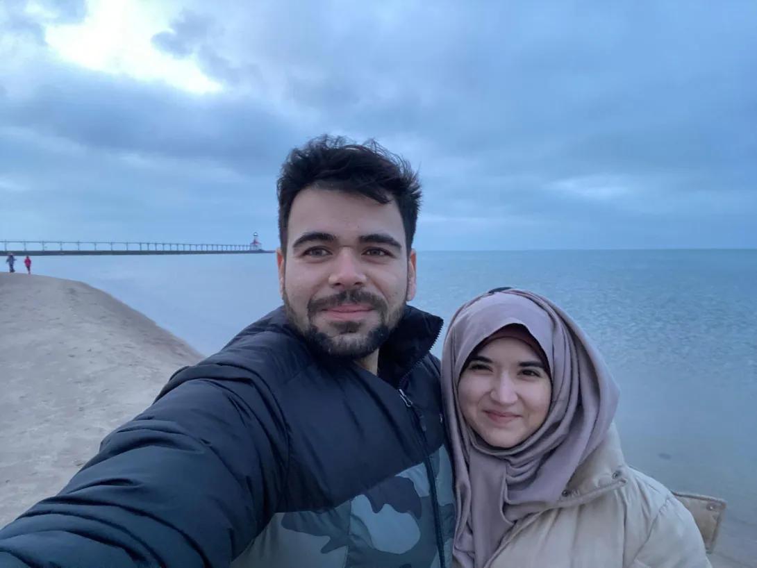 Mahnoor and a friend in front of a bridge on a beach