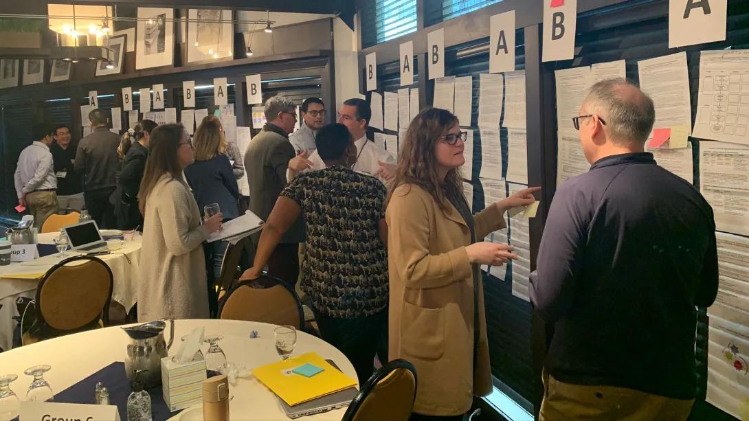 A group of people gather around poster presentations