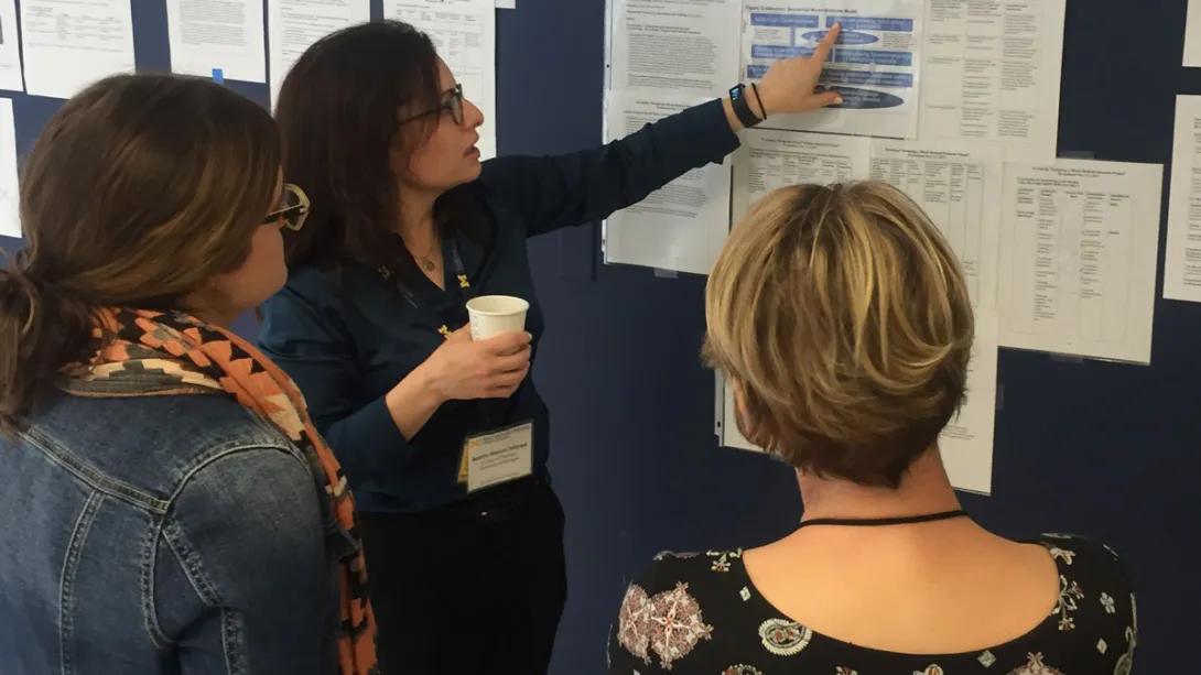 Dr. Watkins speaks at poster presentation with two people