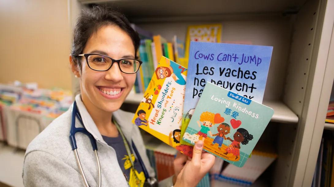 Doctor poses with 3 books up to the camera