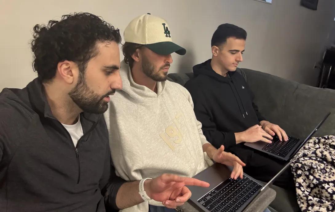 Three medical students sit on a couch working on laptops