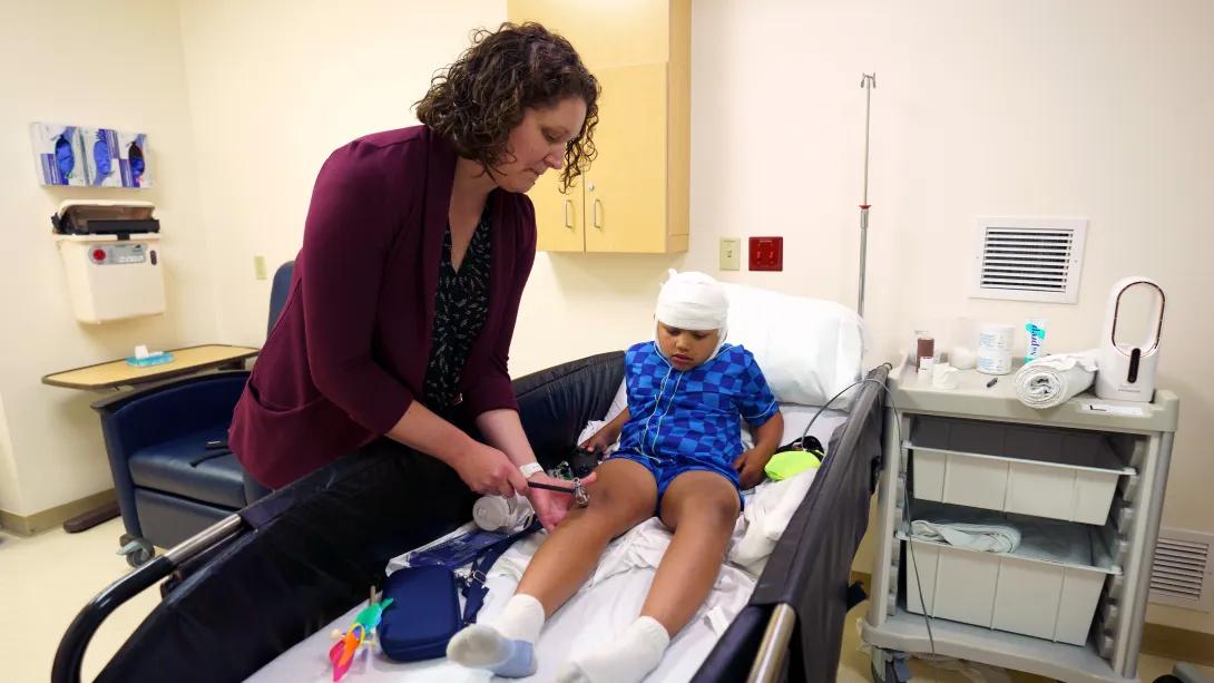 child on hospital bed in patient room with doctor looking at knee