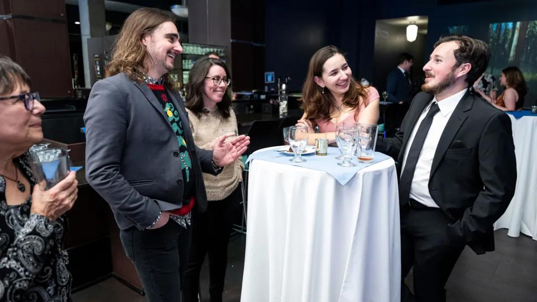 Small group of researchers chat around table at winter formal