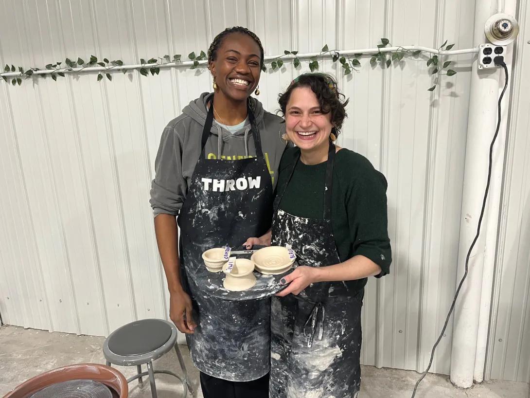 Two women holding freshly thrown pottery