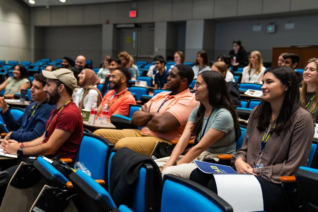 Auditorium full of students listening to a lecture and taking notes