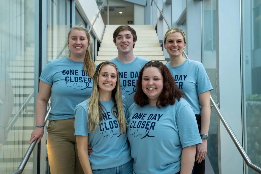 A group of students in blue shirts posing for a photo