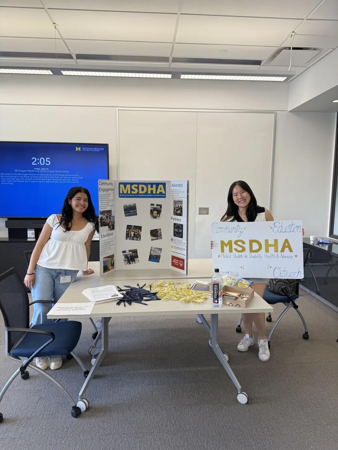 Two medical students with a poster display for MSDHA