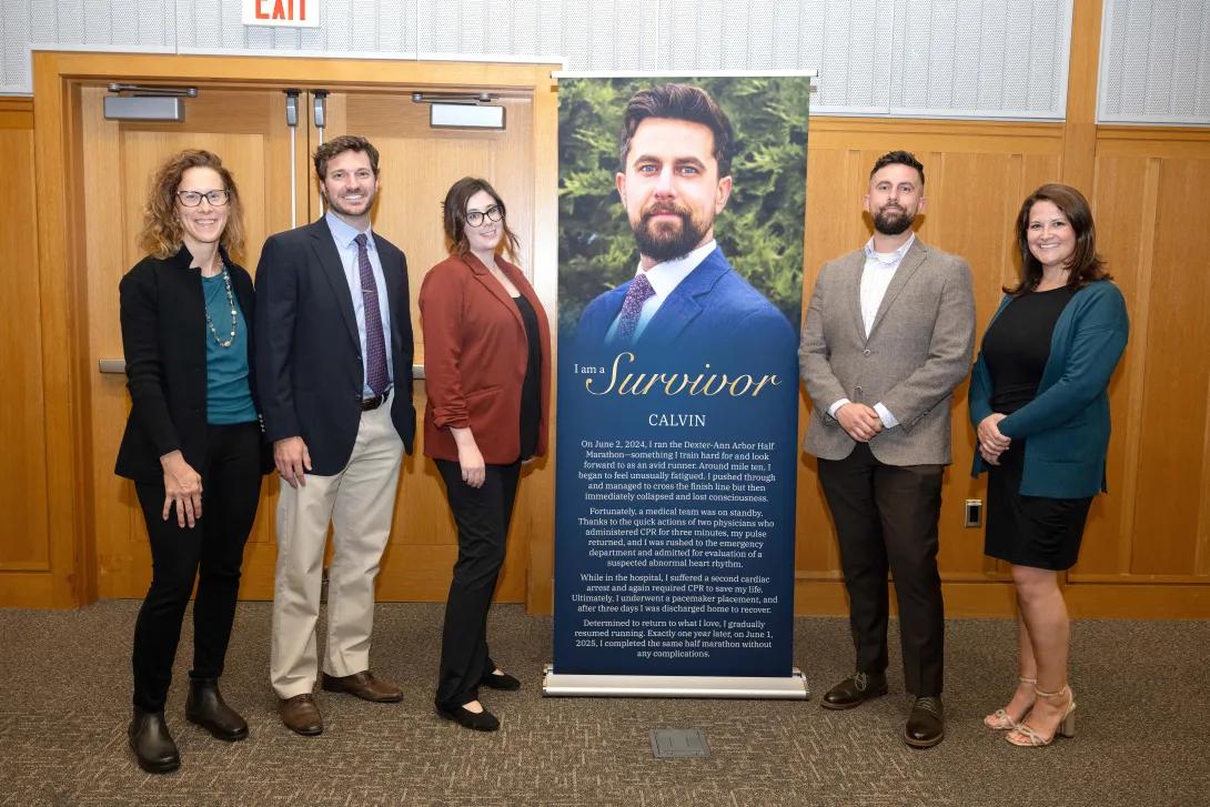 a survivor stands in front of a banner with their story and their care team