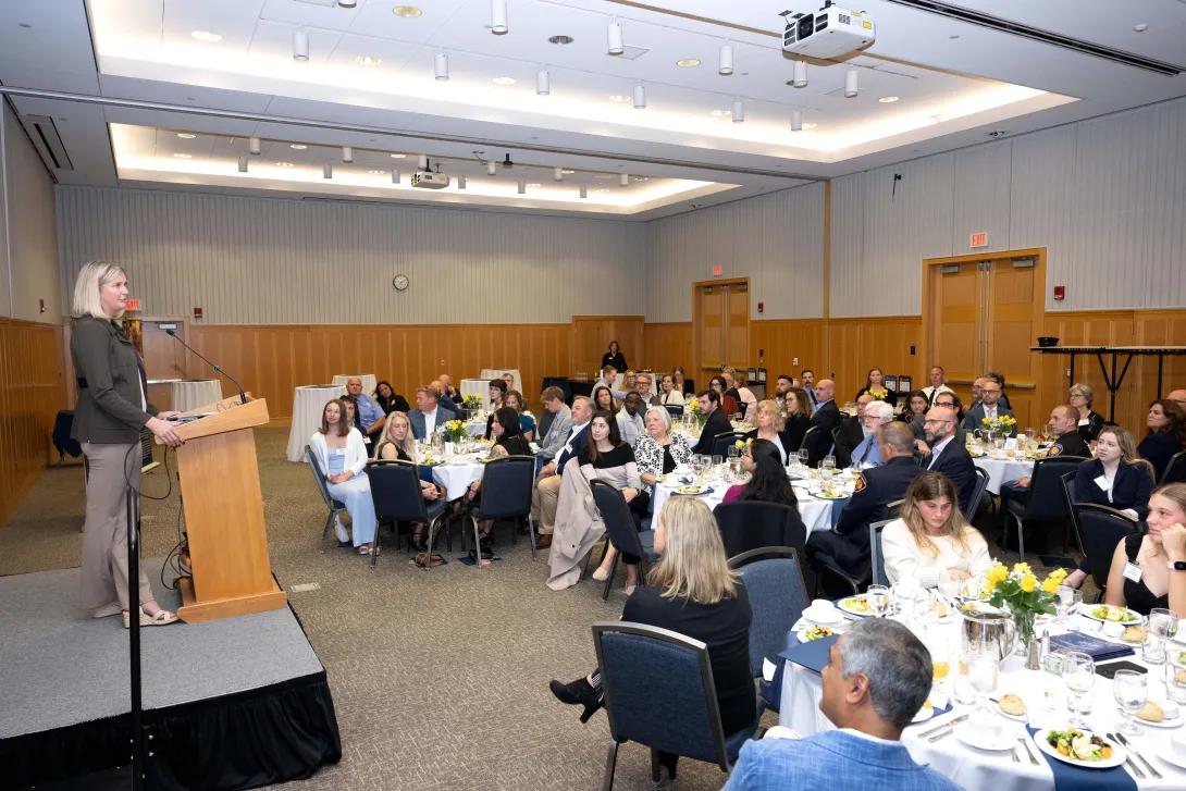 People sit at tables and listen to a speaker