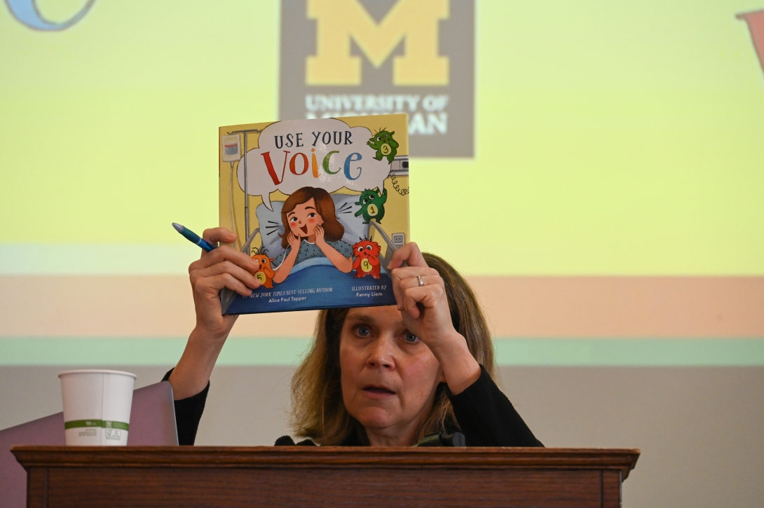Speaker holds up a book.