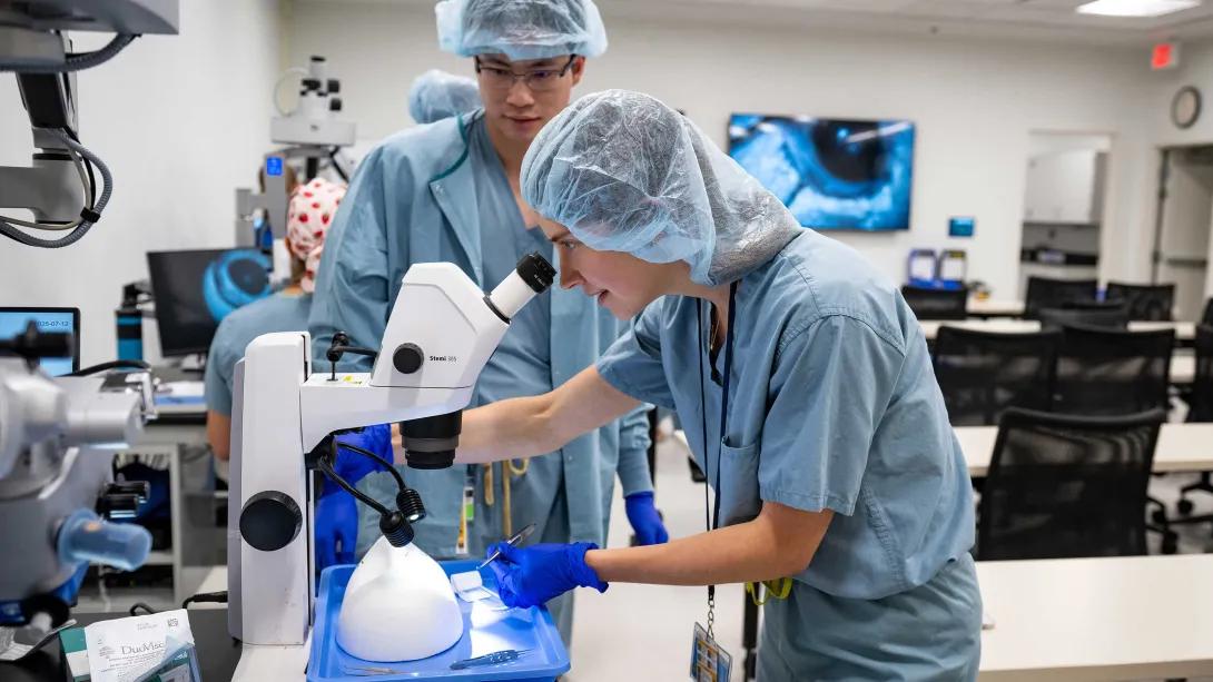 Resident performs simulated eye surgery while another trainee observes in the wet lab.