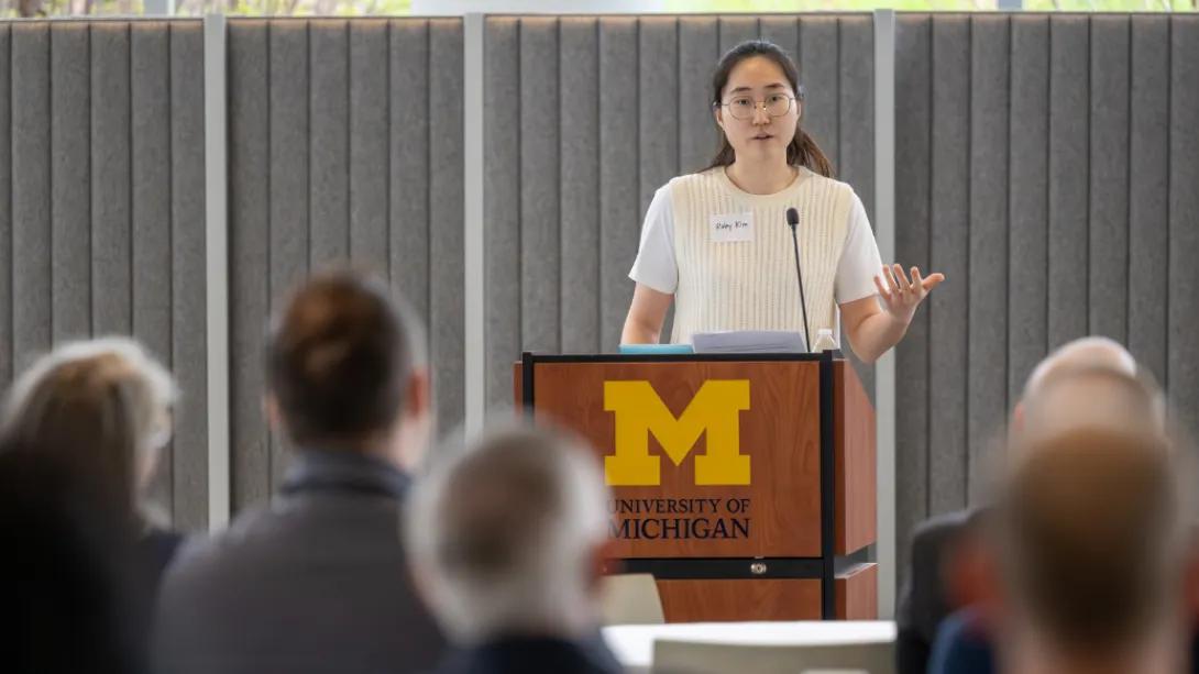 A presenter speaks from a University of Michigan podium to an audience during the Department of Anesthesiology Research Retreat.