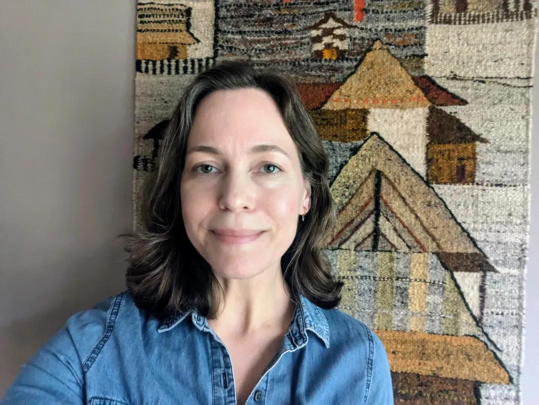 White woman with dark brown, shoulder-length hair, wearing a blue shirt.