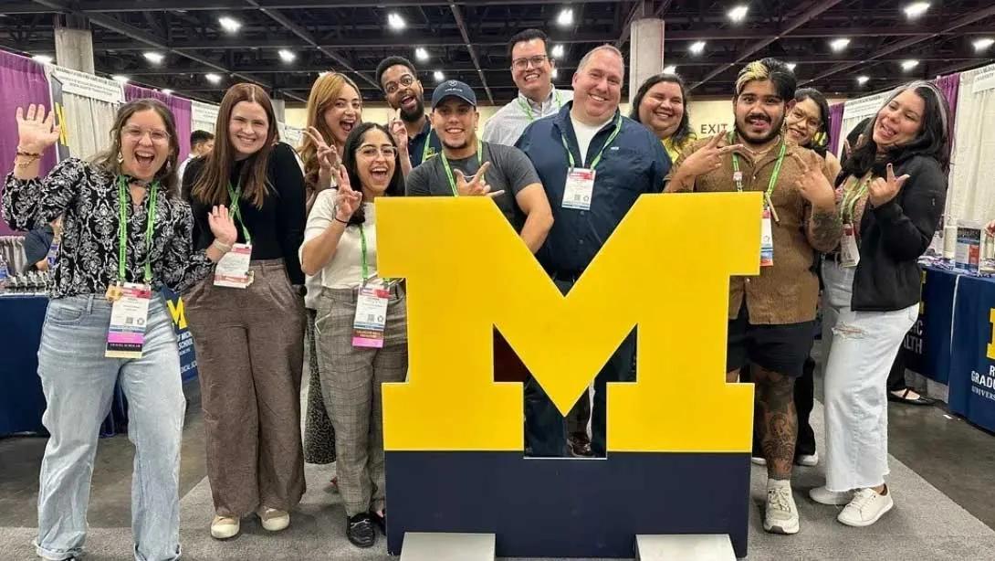 Team members standing around a block M statue