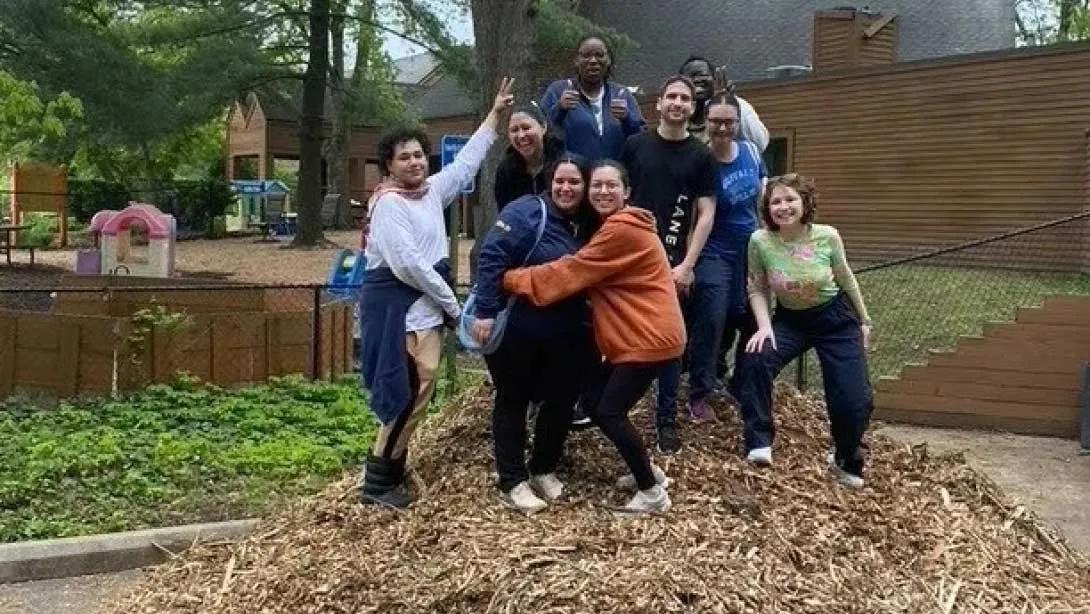 Group of students standing on a huge pile of woodchips